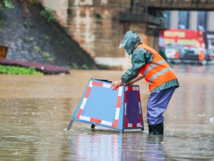 Emergency response team member putting pylons on flooded road